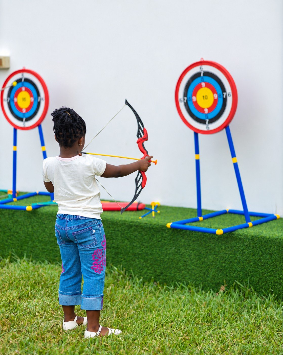 A child playing with a toy archery set on the lawn at a Donna’s Place birthday celebration
